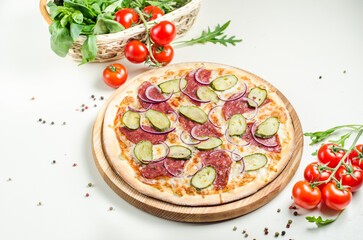 Homemade pizza with sausage, pickles, red onion and cheese on white table. Tasty food