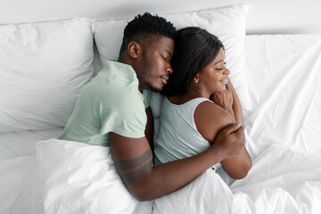 Calm cheerful millennial african american husband hugging his wife and sleeping, relaxing, relax