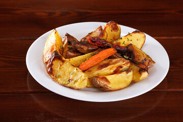 Pieces of baked potatoes with carrots on a white plate.
