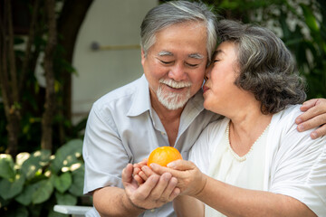 Happy asian elderly couple smiling eat fruit, health care and have a happy life at home after retirement