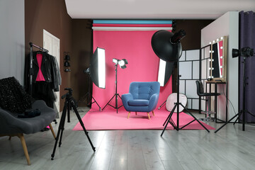 Stylish blue armchair in photo studio with professional equipment