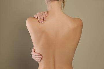 Back view of woman with perfect smooth skin on beige background, closeup. Beauty and body care