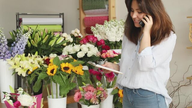 Small business. Female florist taking orders in flower shop. Floral design studio, making decorations and arrangements. Flowers delivery, creating order.