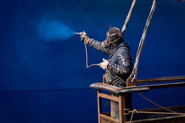 Painters painting a ship at a shipyard
