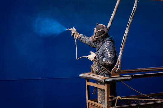 Painters painting a ship at a shipyard
