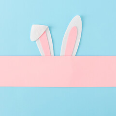 Bunny rabbit ears on pastel pink and blue background, flat lay. Creative Easter minimal concept.