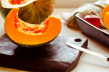 Pumpkin, rustic arrangement with pumpkin cut into pieces, knife, board, wooden spoon, iron pot on a...