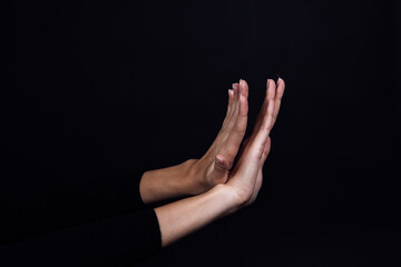 Crossed hands of person on black background showing stop sign. Domestic physical, psychological...