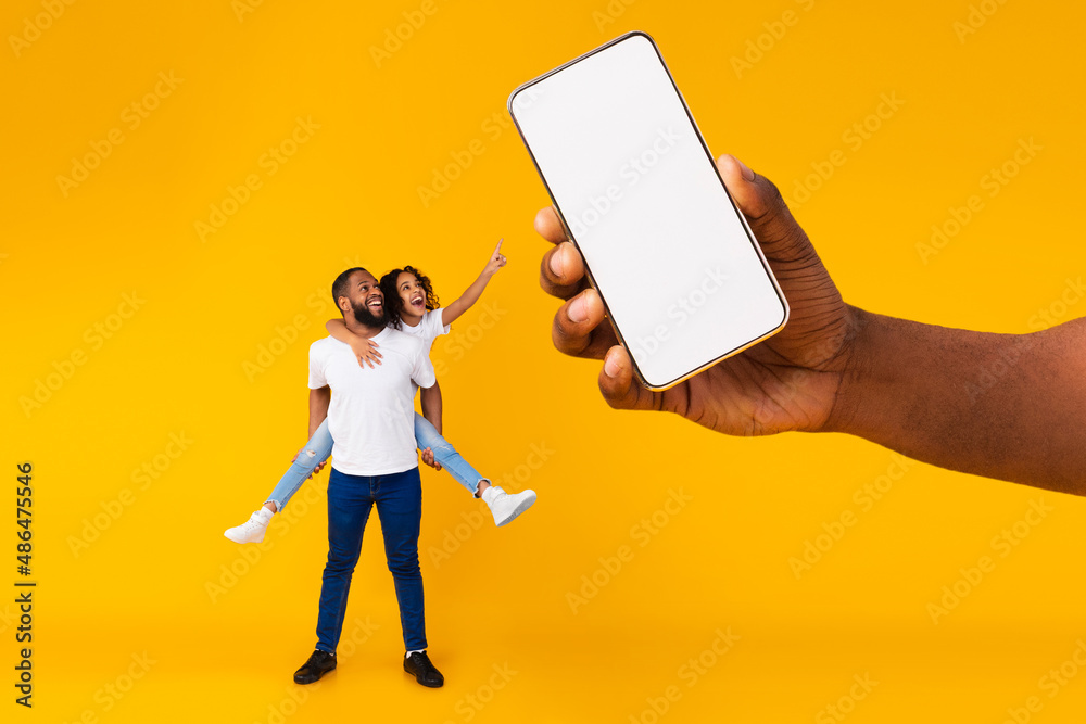 Poster black dad and daughter showing empty smartphone screen for mockup