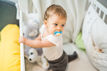 Image of cute baby boy with pacifier  in crib.