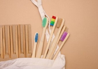 white cotton bag, wooden toothbrushes on a brown background. Recyclable waste, top view