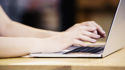 cropped view of young woman typing on laptop in cafe