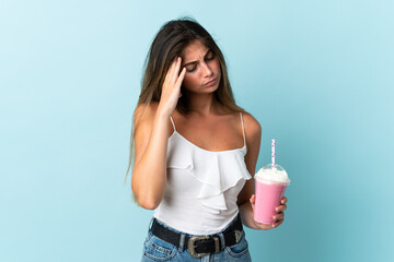 Young woman with strawberry milkshake isolated on blue background with headache