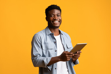 Emotional african american guy holding digital tablet and smiling