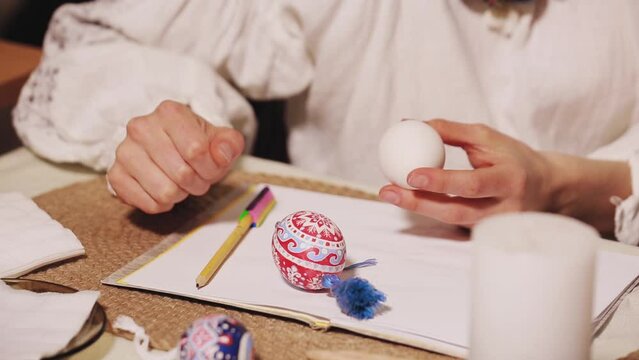 Easter concept. Traditional folk art of making Easter eggs. The woman explains the technique of drawing an ornament on eggs.