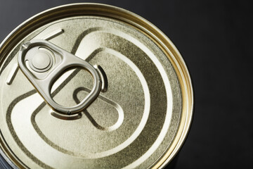 The lid of a metal tin can on a black background