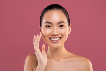 Attractive asian woman touching her face and smiling