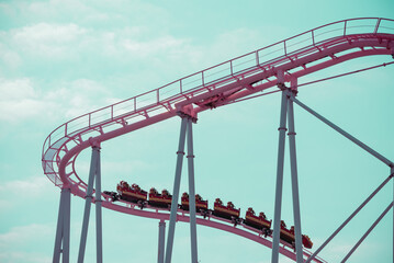 Pink pastel looping roller coaster on blue sky sunny day retro tone. Enjoy travel holiday concept. © pla2na