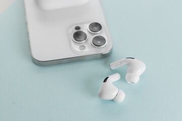 white wireless headphones next to a white smartphone on a blue background