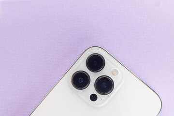 a white smartphone with three cameras lies on a purple background