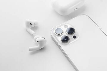 white wireless headphones next to a white smartphone on a white background