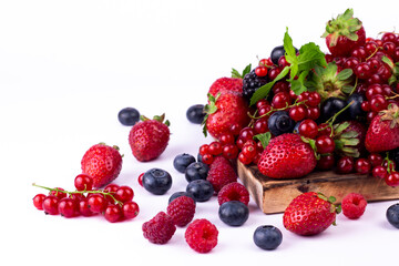 Ripe berries mixed assortment on wooden board on white background. Summer berries background. Cloce up image with copy space.
