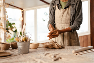 Young black ceramist woman sculpting in clay at her workshop