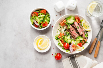 Fresh salad and creamy hummus are topped with  veggies and perfectly grilled steak in this...
