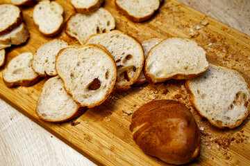 The delicious cut of baguettes on a wooden cutting board on marble.
