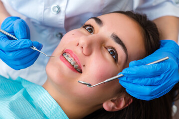 Close up of woman with brackets receiving dental braces treatment in clinic. Orthodontist using...