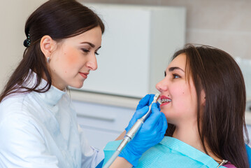 Woman smiling during her dental treatment at dentist. Dental doctors treating a female patient in hospital.