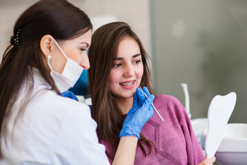 A young woman in a dental clinic with a dentist. The woman with braces smiles. The concept of healthy teeth.