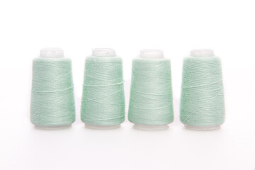Green spool of thread isolated on white background. Skein of woolen threads. Yarn for knitting. Materials for sewing machine. Coil