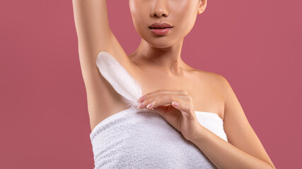 Unrecognizable woman lifting hand up, touching her armpit with feather