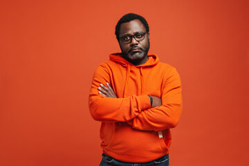 Black sad man in eyeglasses posing with arms crossed