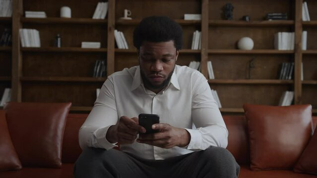 Young adult man thinking and nodding his head in front of his smartphone