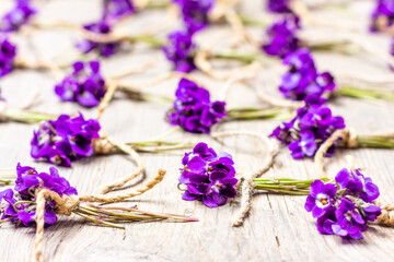 small bouquets of fragrant wild violet flowers tied with twine on a gray wooden background, selective focus