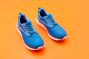 sporty blue sneakers pair on orange background, sport