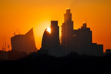 Orange sun setting behind buildings in the City of London.