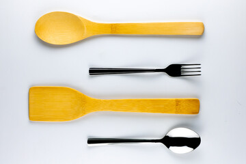Culinary spoon and spatula made of wood with a spoon and fork on a white background. Concept photo.