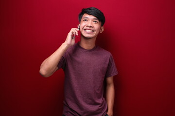 photo of a asian man smiling while receiving a phone. isolated on red background