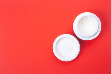Open jar of hand cream on a red background.