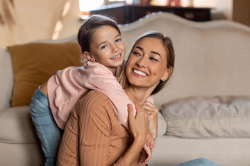 Portrait of happy mom and daughter hugging at home