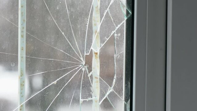 Glass broken by hooligans in a metal-plastic window, close-up