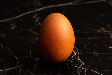 One chicken fresh egg close-up on a dark marble background