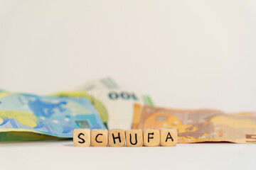 German word for schufa, SCHUFA, spelled with wooden letters wooden cube on a plain white background...