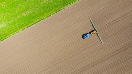 Aerial view on tractor as spraying field with sprayer, herbicide and pesticide