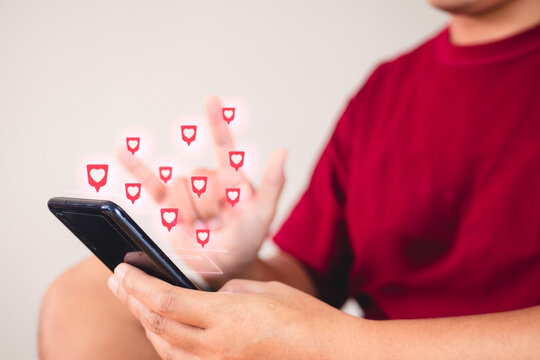 Valentine's day concept. The man uses hand sign to give love thru a smartphone. Heart shape visual effect.