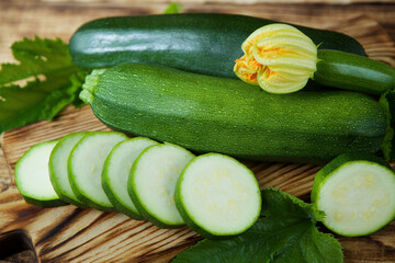The raw product of zucchini lie on the wooden surface of the table. Ingredients for cooking. Seasonal vegetables.