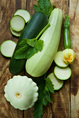 The raw product zucchini zucchini and patissons are on the wooden surface of the table. Ingredients for cooking. Seasonal vegetables.